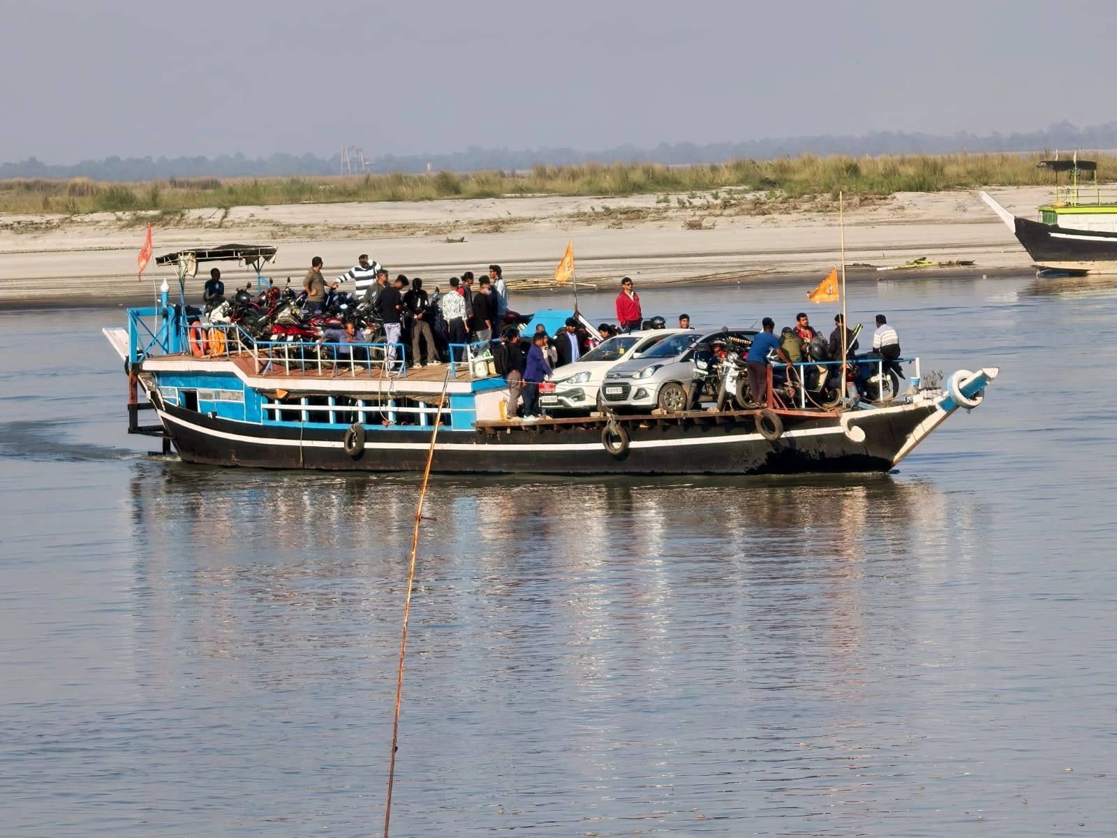 Wooden ferry loaded with cars, motorcycles and passengers crossing the Brahmaputra river towards Majuli Island, Assam
